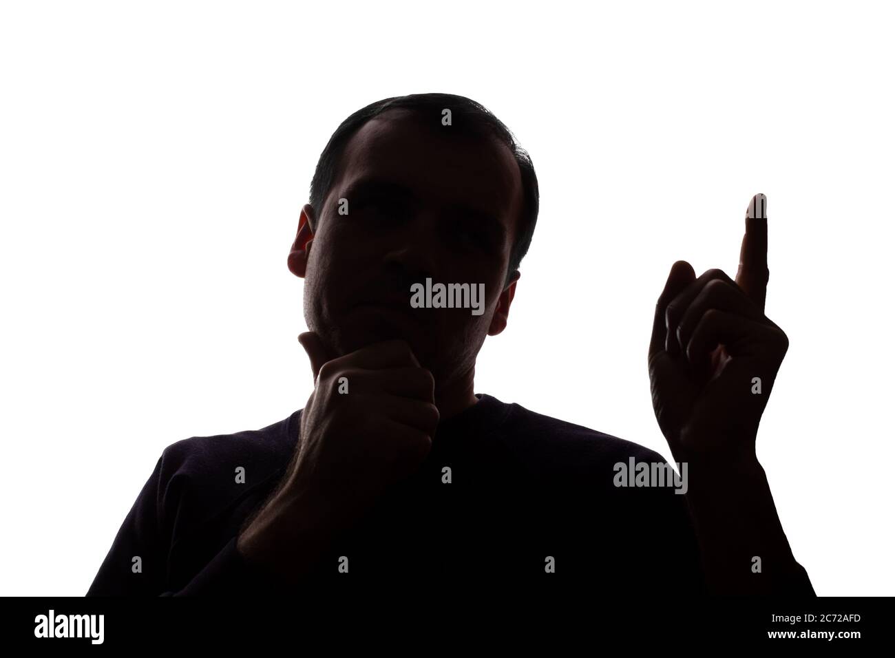 Porträt eines jungen Mannes, unrasiert, Vorderansicht hob seinen Zeigefinger nach oben Idee - dunkel isoliert Silhouette Stockfoto