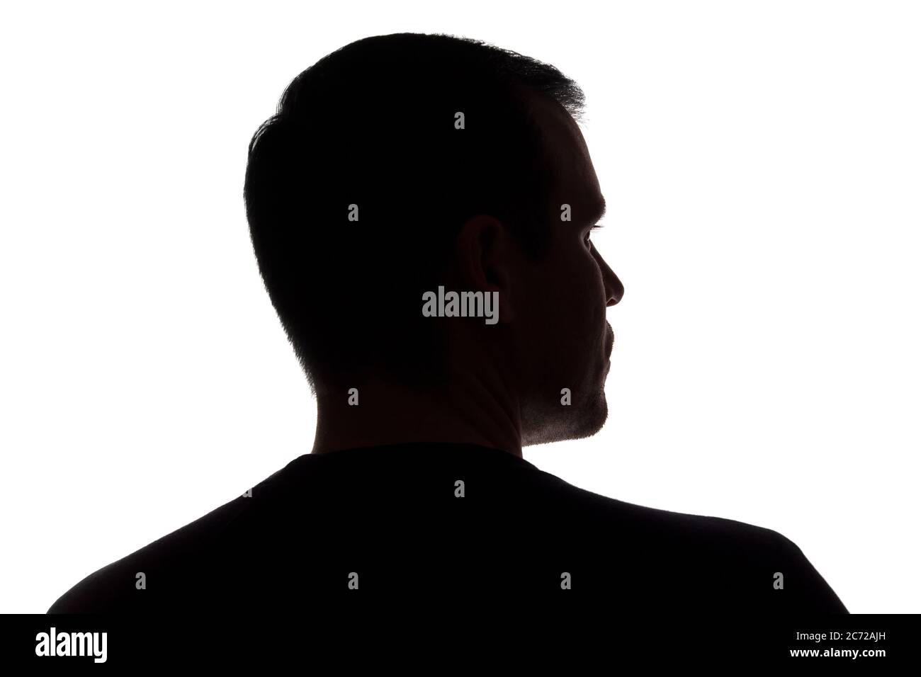 Porträt eines jungen Mannes, unrasiert, Rückansicht - dunkel isoliert Silhouette Stockfoto