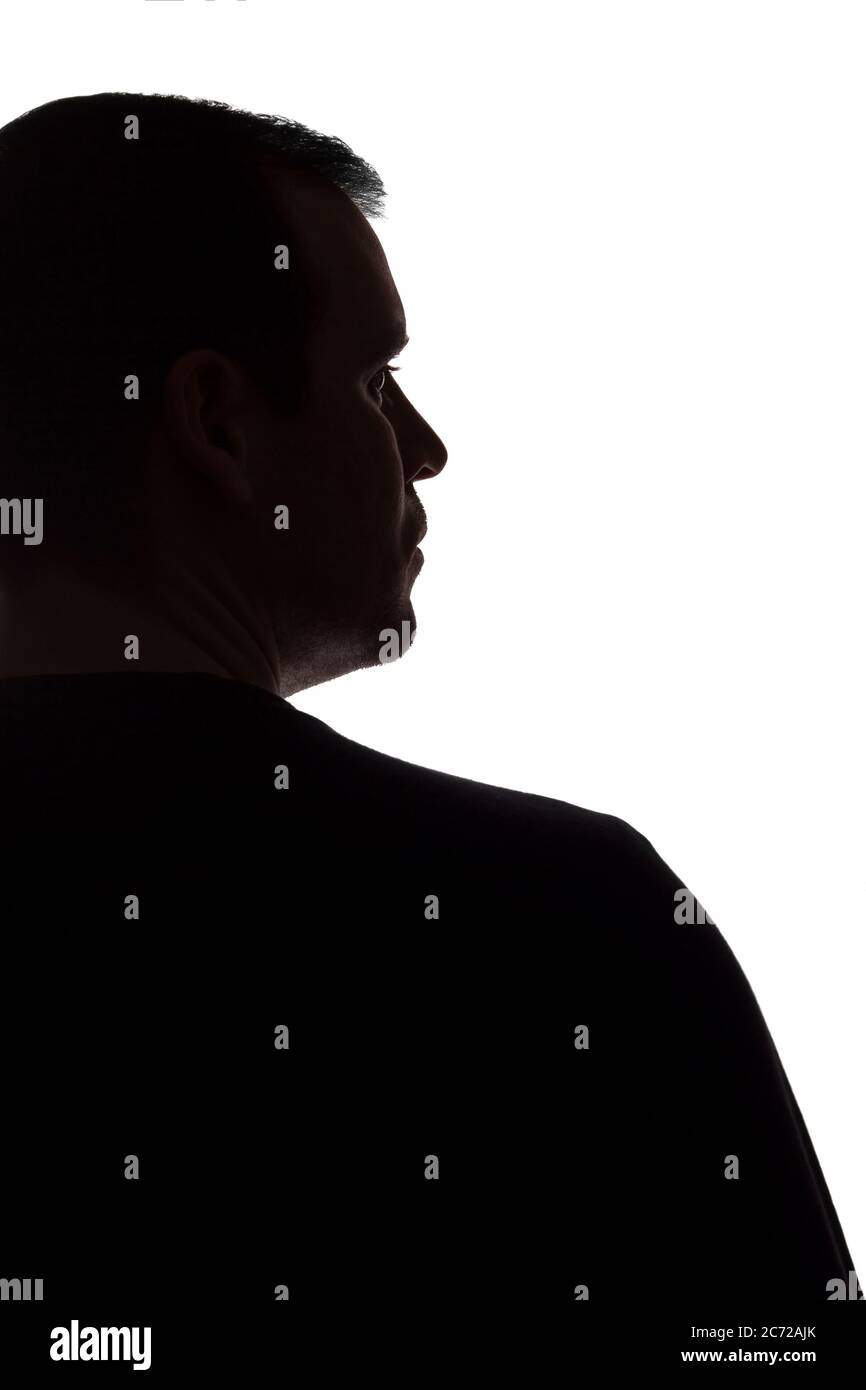 Porträt eines jungen Mannes, unrasiert, Rückansicht - dunkel isoliert Silhouette Stockfoto