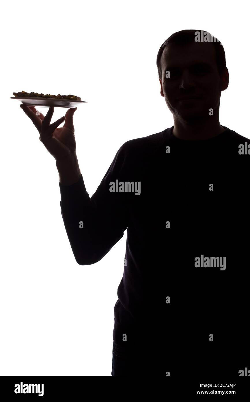 Portrait Lächeln junger Mann mit Pizza auf einem Teller in der Hand, unrasiert, Seitenansicht - dunkel isoliert Silhouette Stockfoto