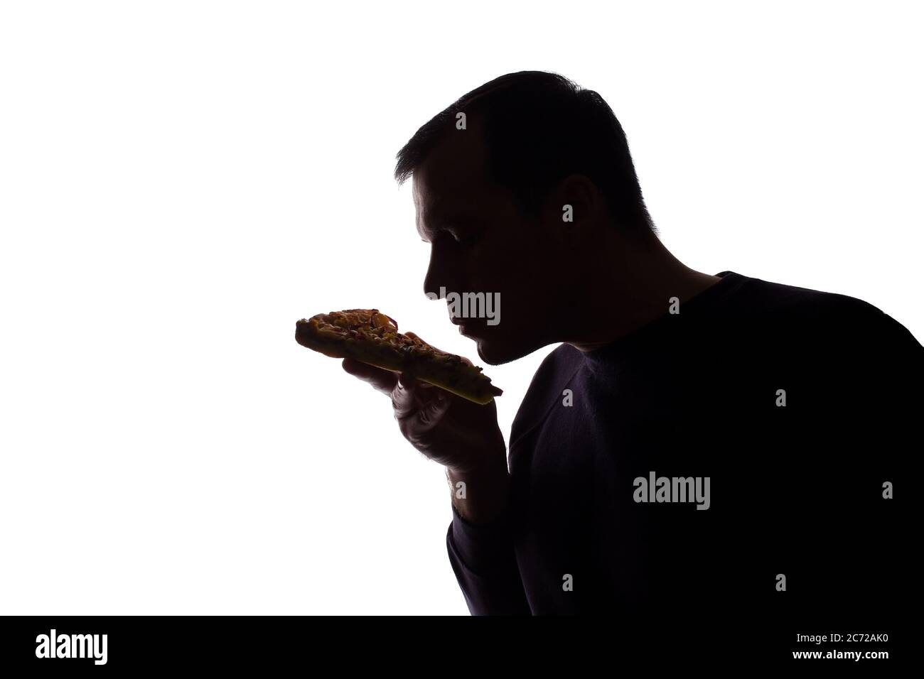 Porträt eines jungen Mannes zufrieden mit dem Geschmack von Pizza, unrasiert, Seitenansicht - dunkel isoliert Silhouette Stockfoto