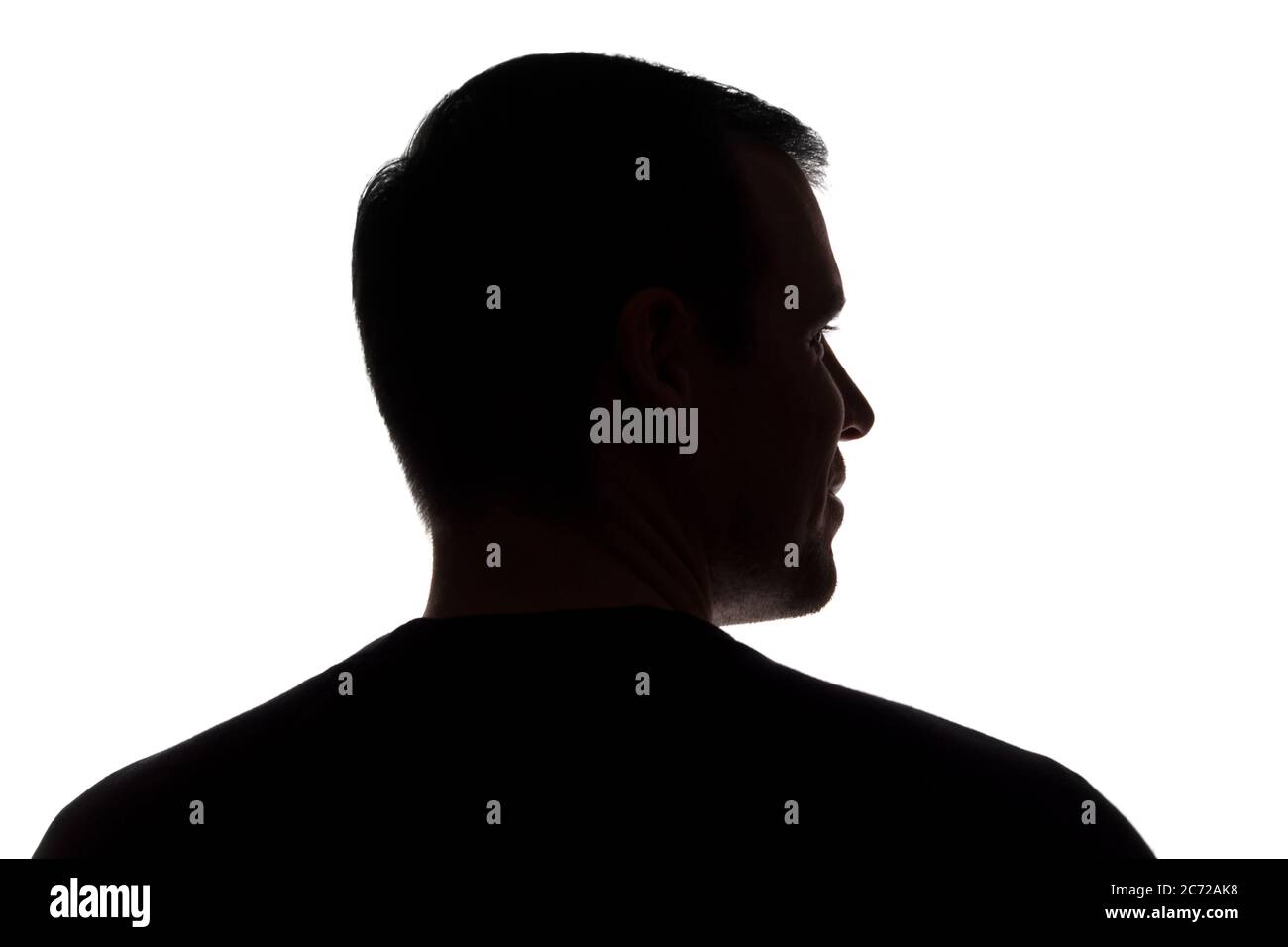 Porträt eines jungen Mannes, unrasiert, Rückansicht - dunkel isoliert Silhouette Stockfoto