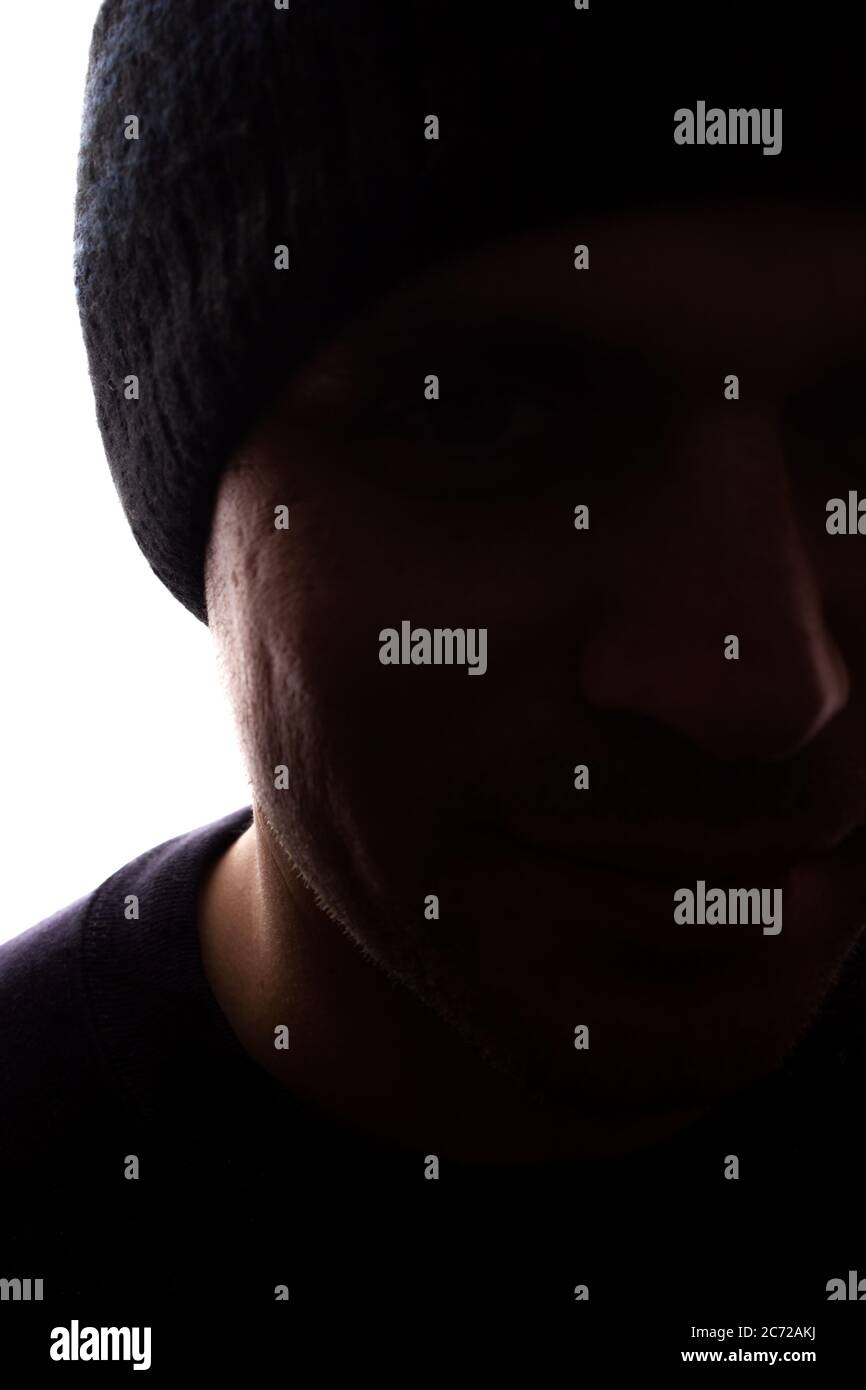 Porträt eines jungen Mannes, unrasiert, Seitenansicht in Mütze - dunkel isolierte Silhouette Stockfoto