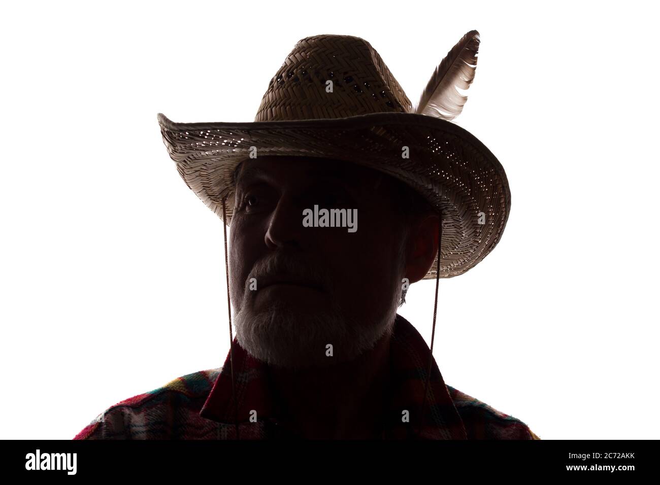 Porträt eines alten Mannes, in einem Cowboy Hut mit Feder, mit Bart, Vorderansicht - dunkel isoliert Silhouette Stockfoto