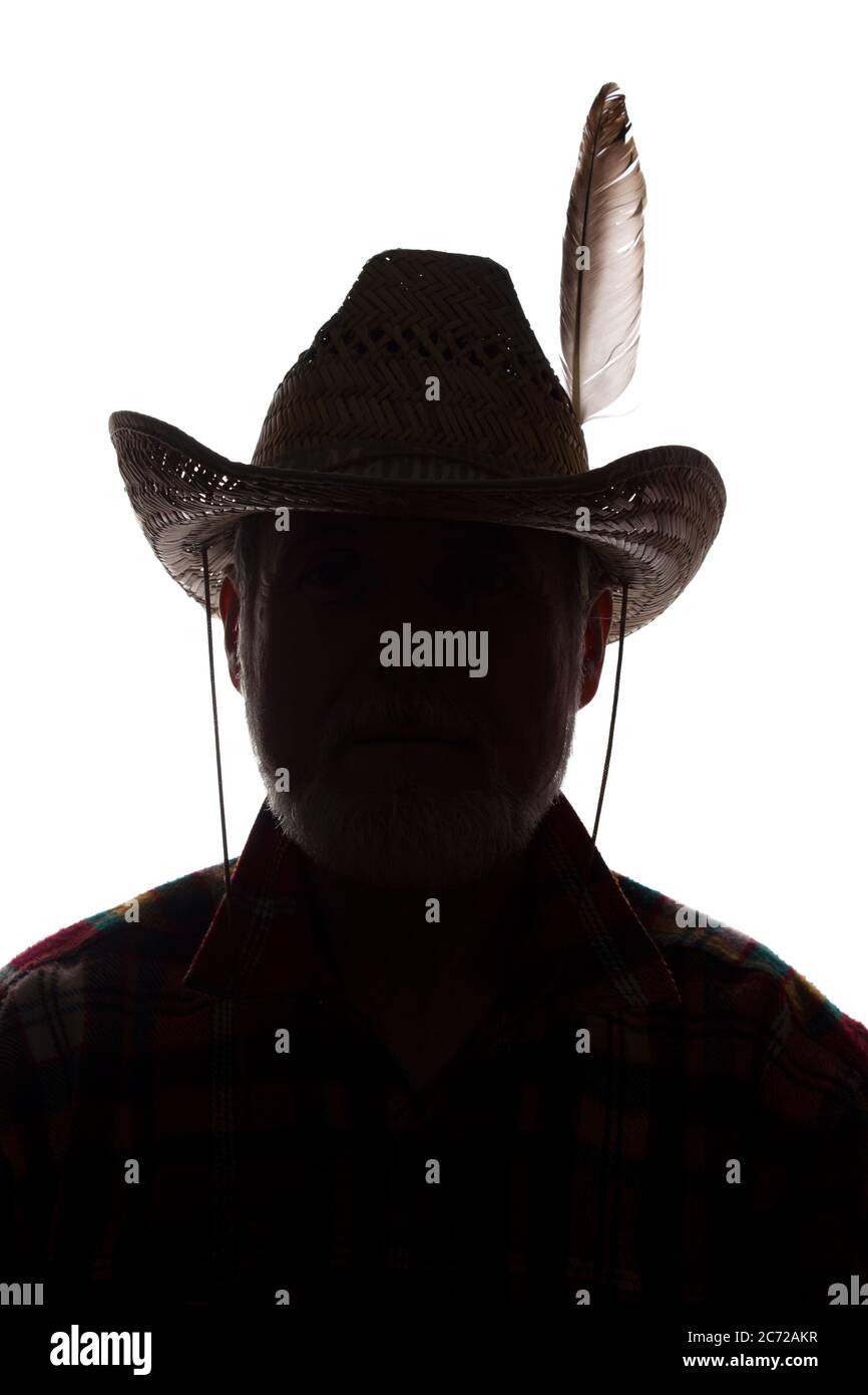Porträt eines alten Mannes, in einem Cowboy Hut mit Feder, mit Bart, Vorderansicht - dunkel isoliert Silhouette Stockfoto