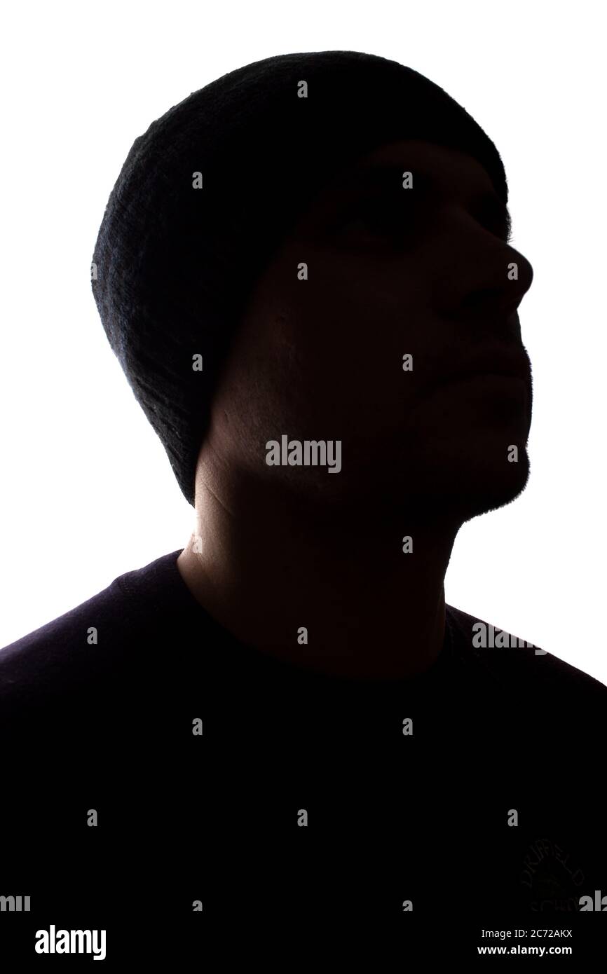 Porträt eines jungen Mannes, unrasiert, Seitenansicht in Mütze - dunkel isolierte Silhouette Stockfoto