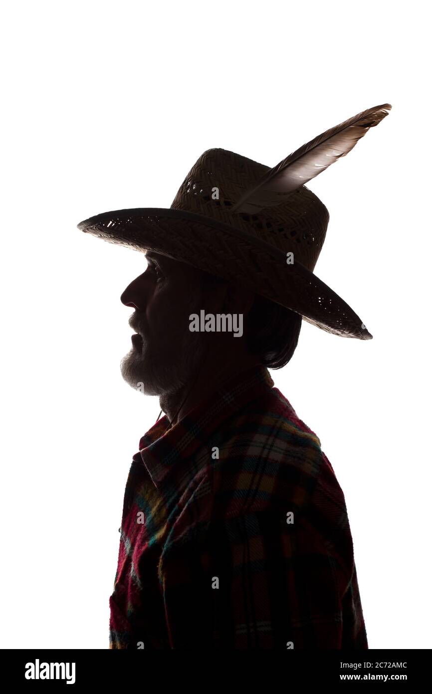 Porträt eines alten Mannes, in einem Cowboy Hut mit Feder, mit Bart, Seitenansicht - dunkel isoliert Silhouette Stockfoto