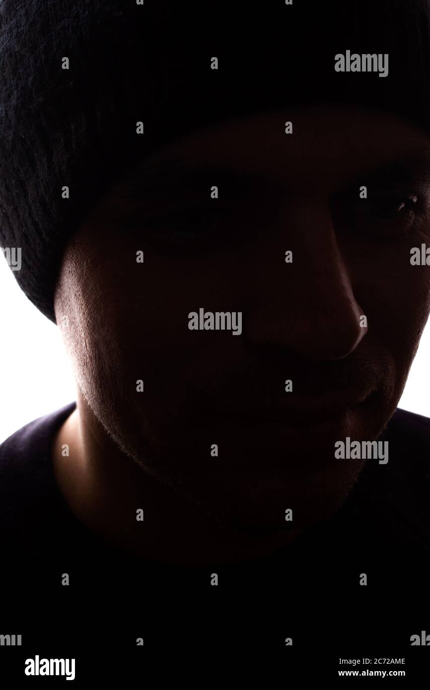 Porträt eines jungen Mannes, unrasiert, Seitenansicht in Mütze - dunkel isolierte Silhouette Stockfoto