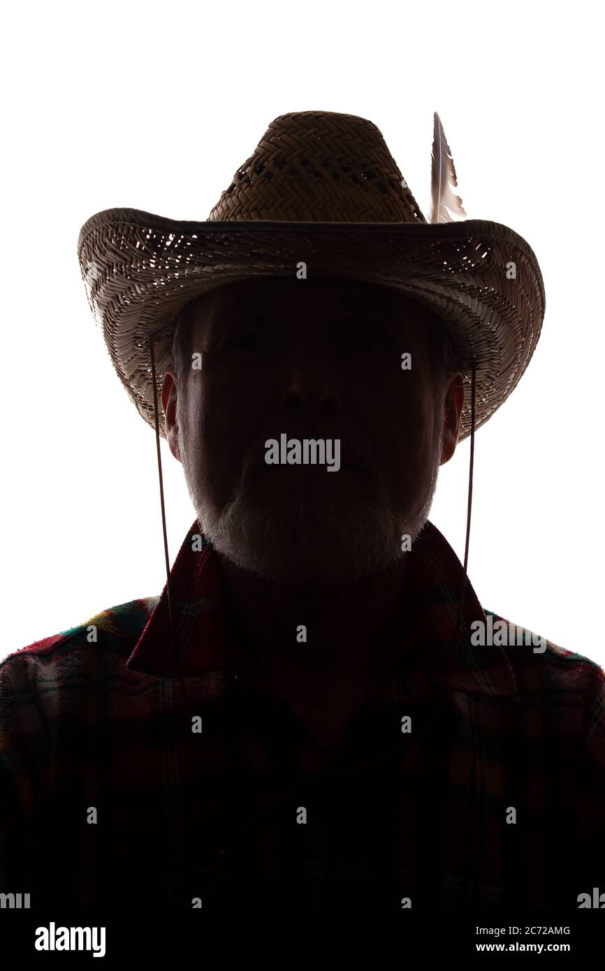 Porträt eines alten Mannes, in einem Cowboy Hut mit Feder, mit Bart, Vorderansicht - dunkel isoliert Silhouette Stockfoto