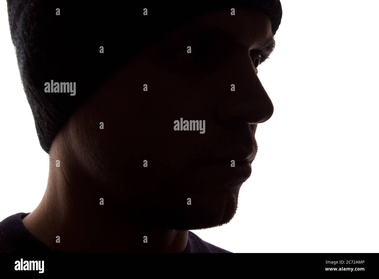 Porträt eines jungen Mannes, unrasiert, Seitenansicht in Mütze - dunkel isolierte Silhouette Stockfoto