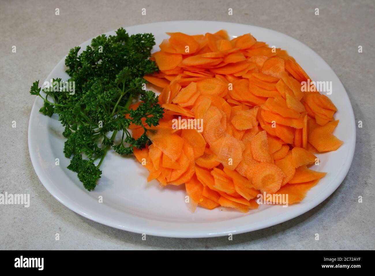 Vegane und vegetarische Speisen. Platte von Rohheit mit in Scheiben geschnittenen Karotten mit Zweigen der Petersilie. Stockfoto