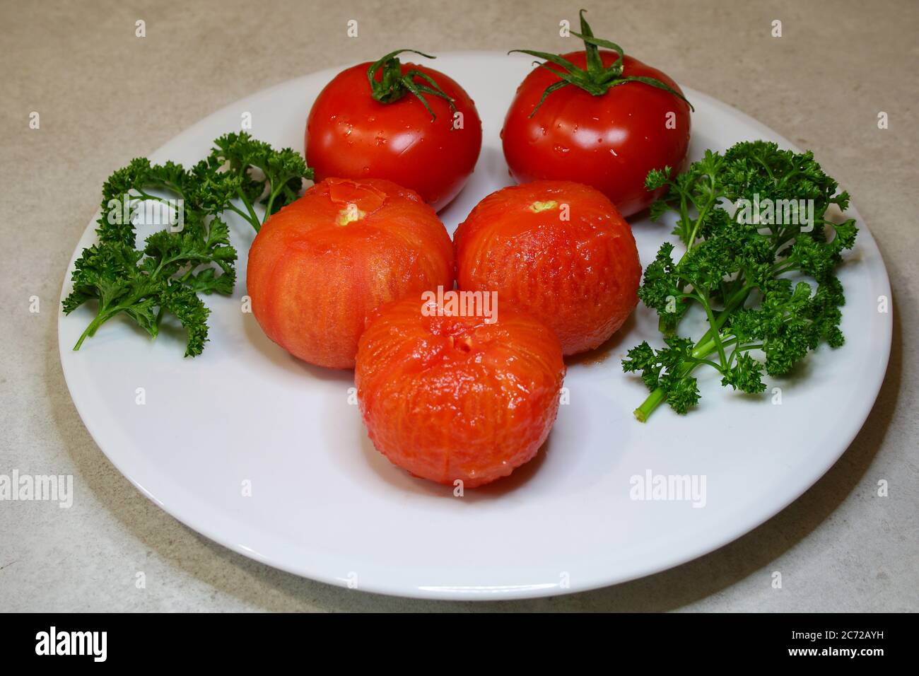 Vegane Küche. Vegetarische Gerichte. Platte von Rohheit. Tomaten frisch rot und geschält nach dem Kochen. Zweige der grünen Petersilie. Stockfoto
