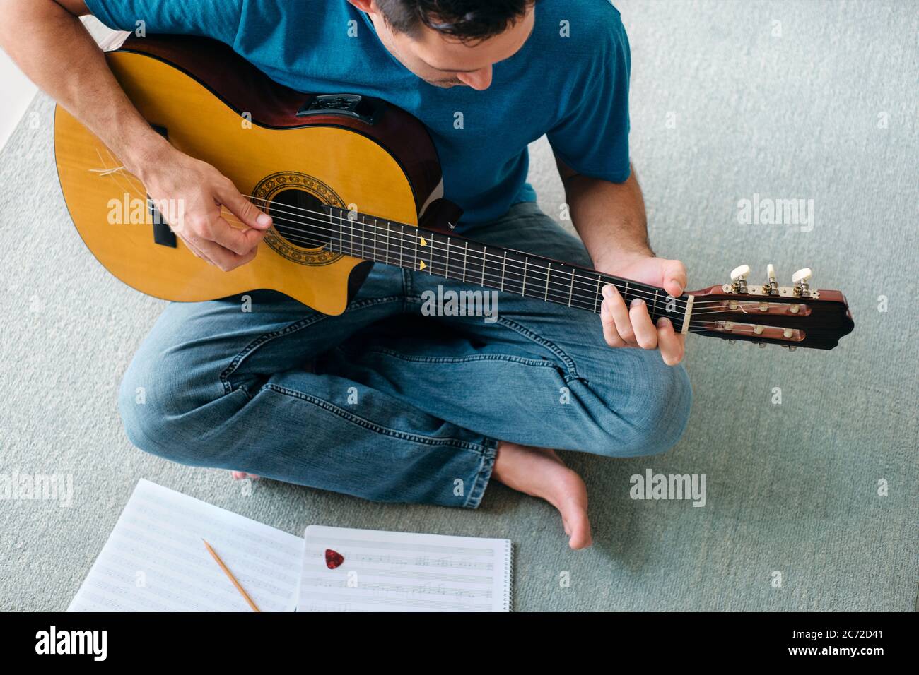 Mid Adult Man Reading Akustische Gitarre Noten In Wohnung Stockfoto