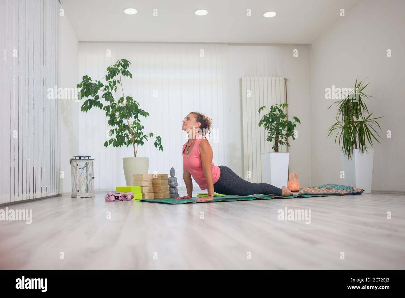 Eine junge Frau mittleren Alters, die Yoga praktiziert, drinnen im Yoga-Studio, nach oben gerichtete Hundehaltung. Stockfoto