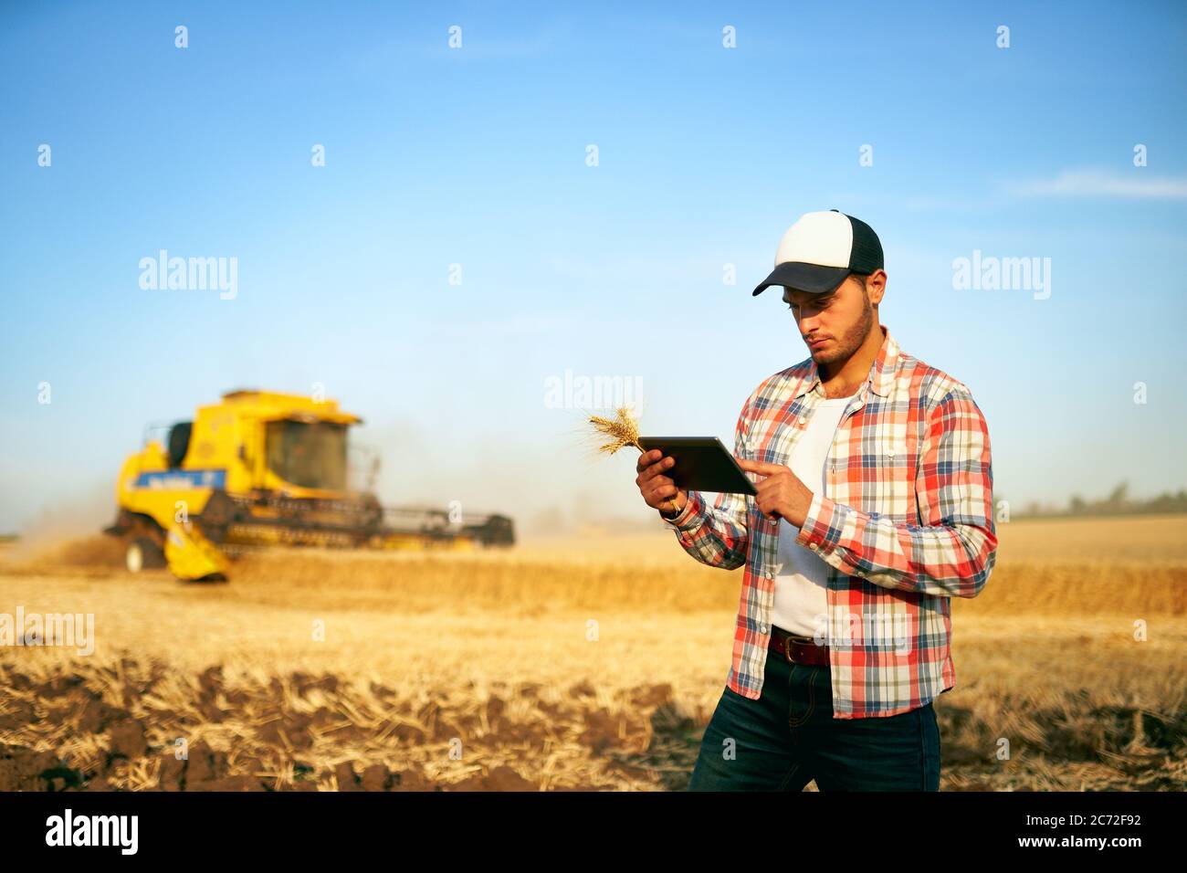 Präzisionslandwirtschaft. Landwirt hält Tablet für Mähdrescher Führung und Steuerung mit modernen Automatisierungssystem. Agronom mit Online-Daten Stockfoto
