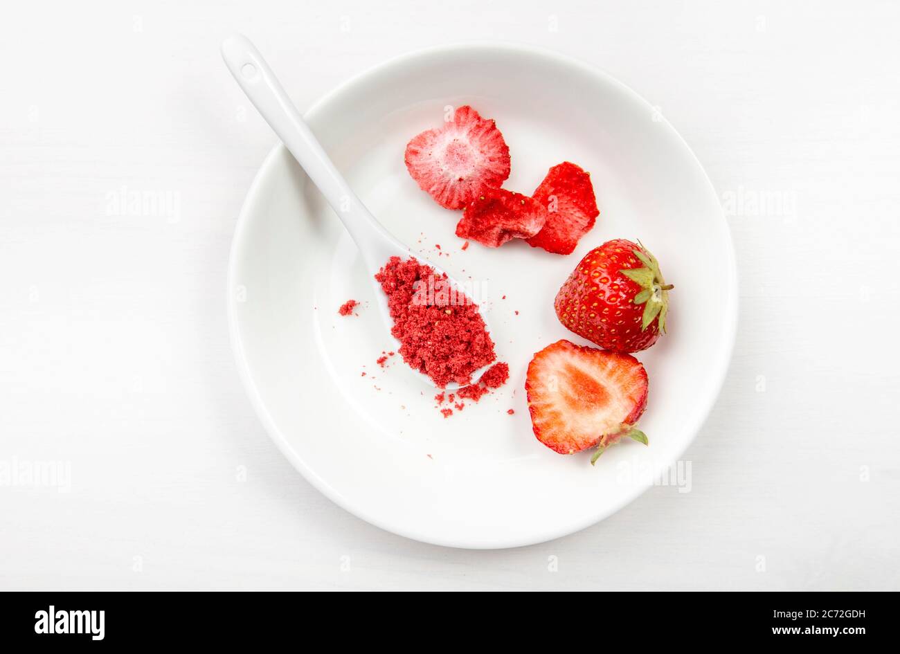 Erdbeerpulver aus gefriergetrockneten Erdbeeren zum Streuen. Geschmack und Farbe Zutat für Lebensmittel. Draufsicht, weißer minimaler Hintergrund, Kopierbereich Stockfoto