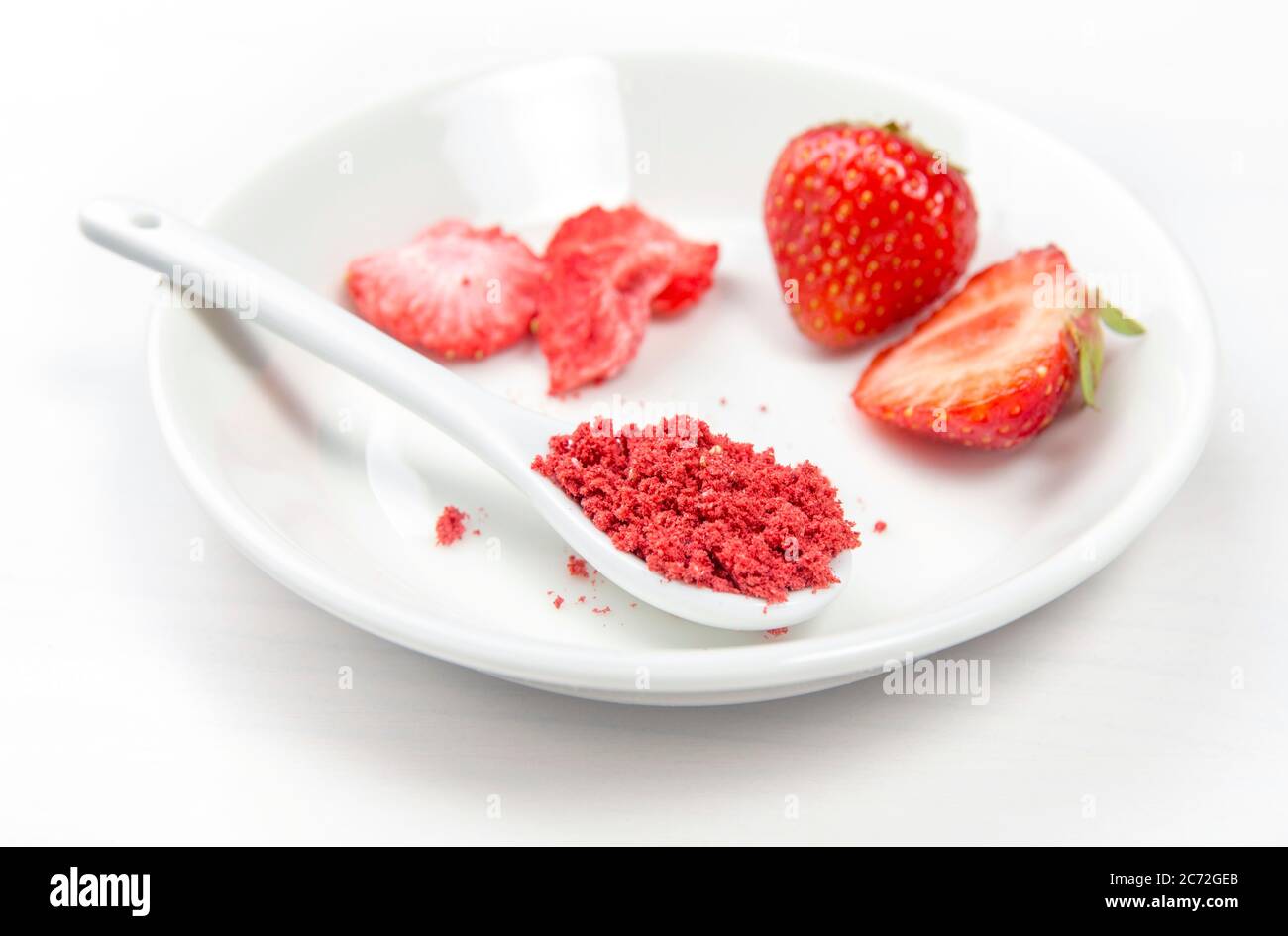 Erdbeerpulver aus gefriergetrockneten Erdbeeren zum Streuen. Geschmack und Farbe Zutat für Lebensmittel. Draufsicht, weißer minimaler Hintergrund, Kopierbereich Stockfoto