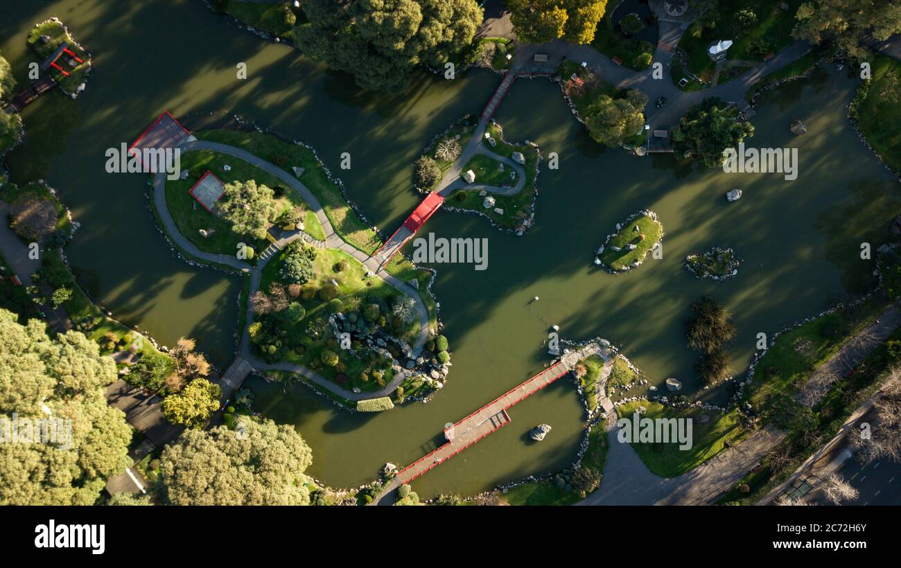 Ein Luftbild von oben nach unten auf den japanischen Garten mit orientalischen Architektur Akzenten mit dem grünen Seenwasser während des Sonnenuntergangs an einem sonnigen Tag. Stockfoto