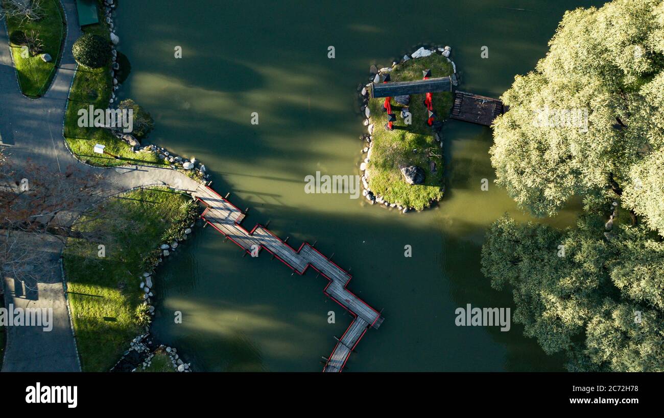 Ein Luftbild von oben nach unten auf japanischen Schrumpfschlauch und rote Brücke auf dem grünen See Wasser während des Sonnenuntergangs an einem sonnigen Tag. Stockfoto