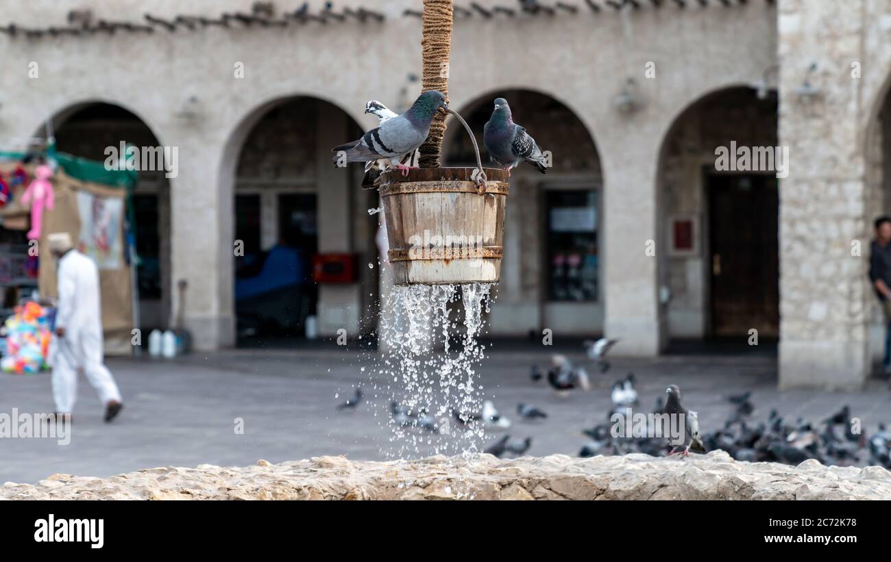 Doha, Katar - Februar 2019: Der alte Brunnen Brunnen Brunnen und Tauben vor Al Fanar Gebäude, in Souq Waqif, Doha, Katar. Stockfoto