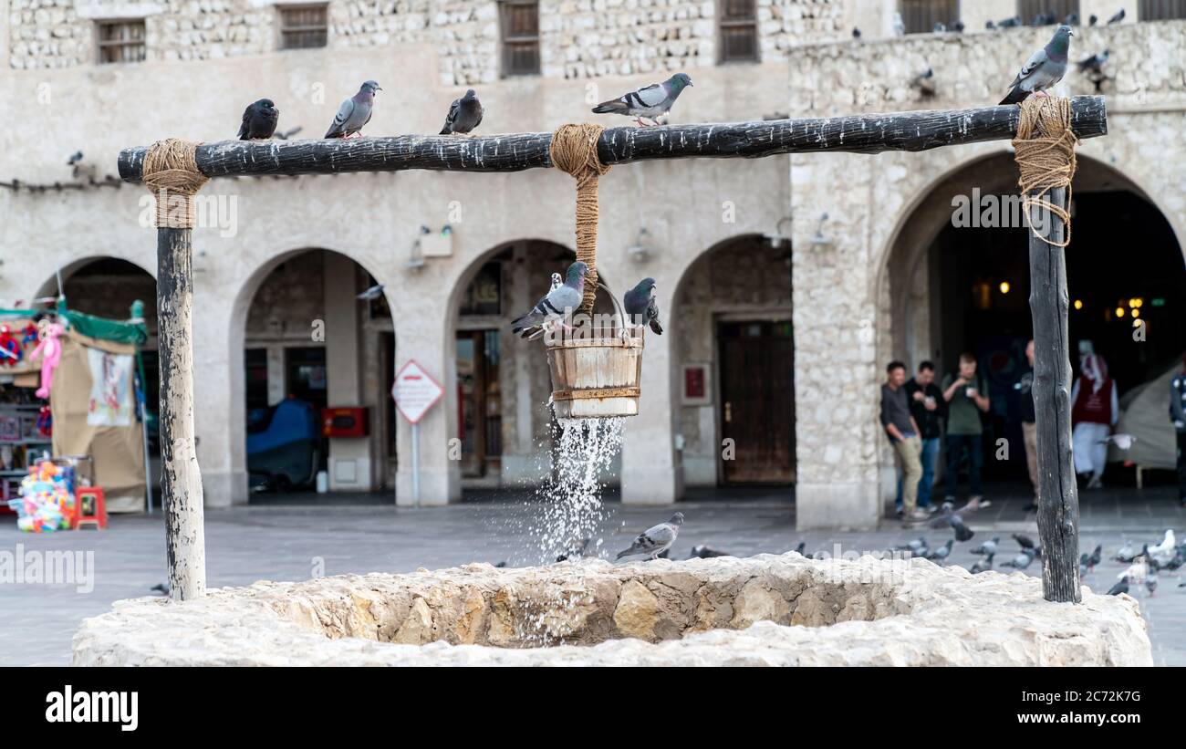Doha, Katar - Februar 2019: Der alte Brunnen Brunnen Brunnen und Tauben vor Al Fanar Gebäude, in Souq Waqif, Doha, Katar. Stockfoto