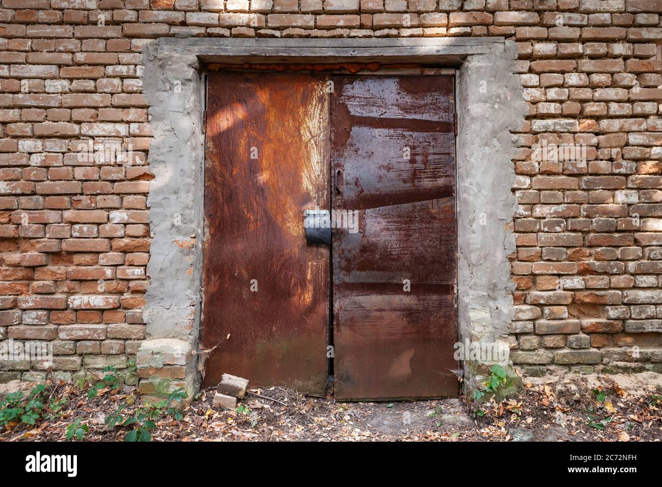 Nahaufnahme der alten verrosteten Tür und Ziegelwand. Stockfoto