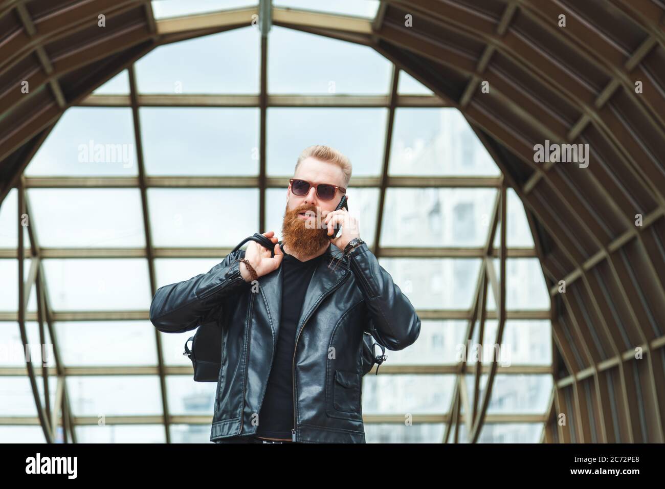Stilvoll gekleideter junger Mann mit einem Bart, der am Telefon spricht. Stockfoto