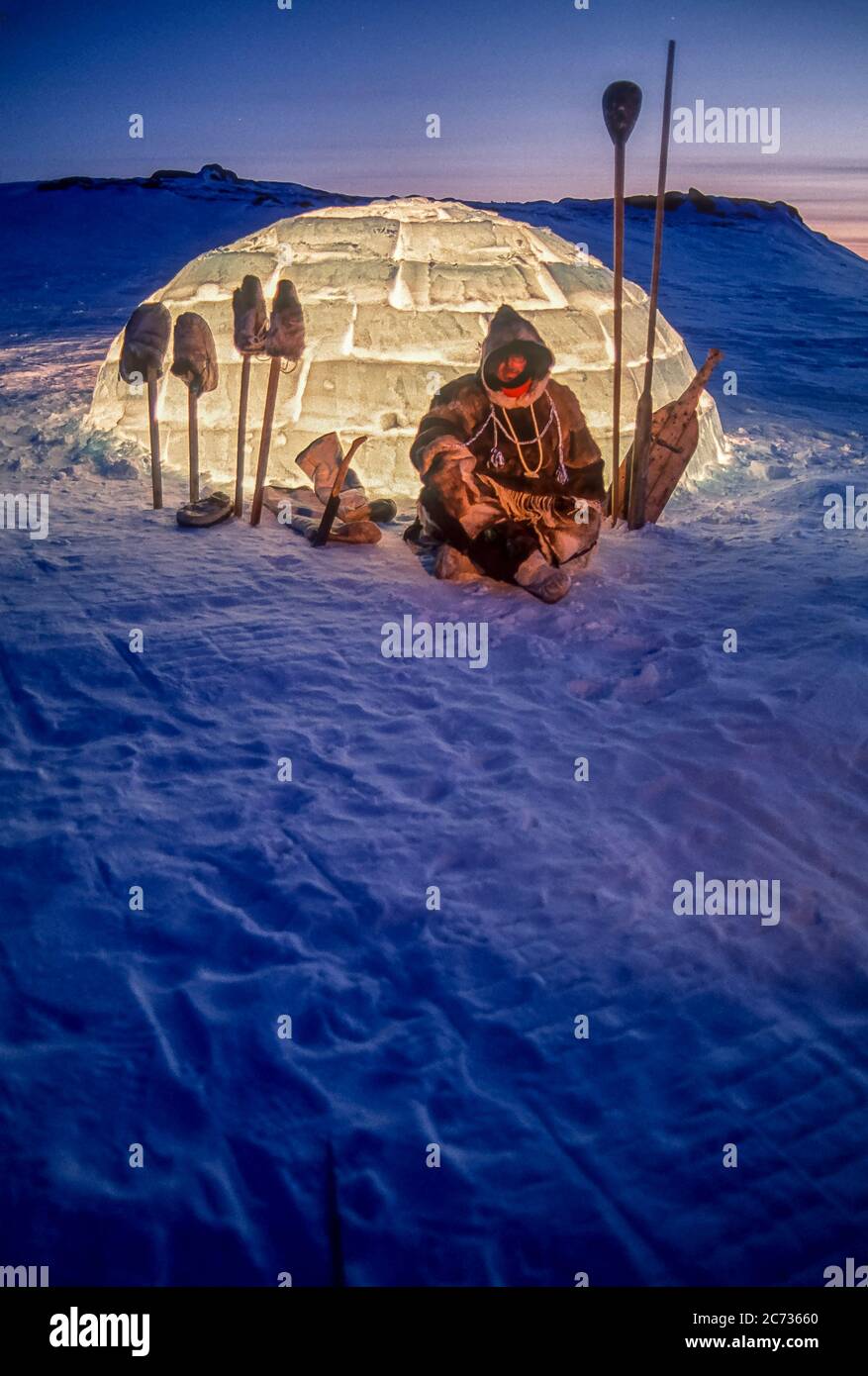 Inuit Mann und Werkzeuge Silhouetten gegen ein brenntes Iglu in der Dämmerung außerhalb Baker Lake, Nunavut. Stockfoto