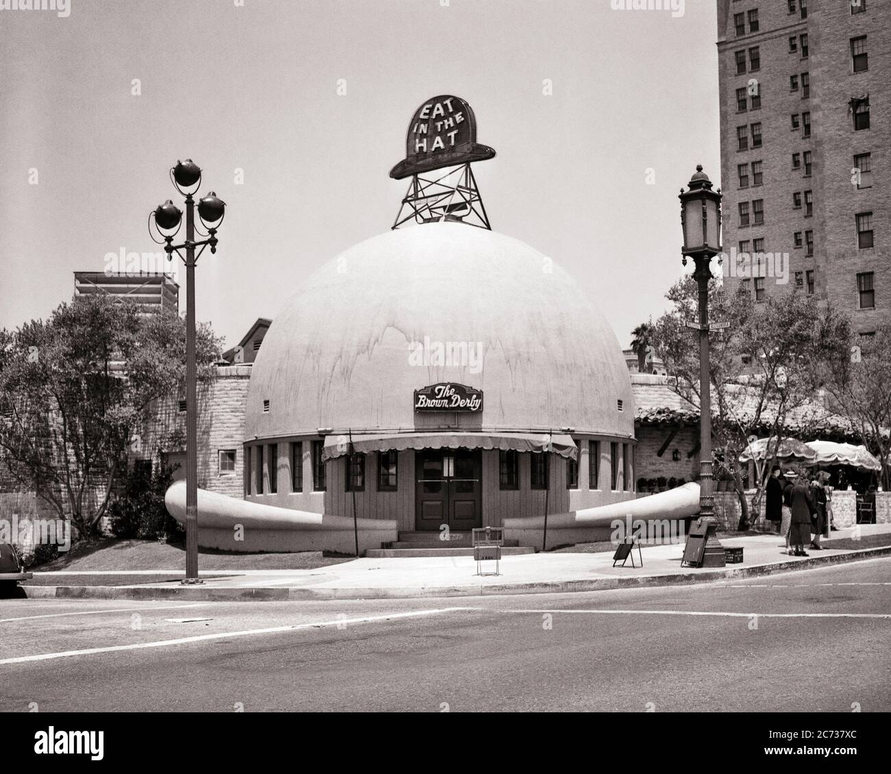 1940ER JAHRE FRONT ENTRANCE AND EXTERIOR OF BROWN DERBY RESTAURANT OPENED 1926 ON WILSHIRE BOULEVARD DEMOLED 1980 LOS ANGELES CA USA - ASP JO7700 ASP001 HARS VEREINIGTE STAATEN VON AMERIKA SYMBOLE FORM B&W NORDAMERIKA BIZARRER NORDAMERIKANISCHER ERFOLG WEITWINKEL BOULEVARD HUMORVOLLE SELTSAME DERBY FREIZEIT KUNDENSERVICE GEÖFFNET UND NETWORKING AUFREGUNG EXTERIEUR BERÜHMTEN ZANY KOMISCHEN STOLZ UNKONVENTIONELLE 1926 VON AUF CA UNVERWECHSELBAREN KONZEPT ORIGINAL KONZEPTUELLE PROMI-KOMÖDIE STILVOLL ABGEDREHT EIGENWILLIGE SYMBOLISCH AMÜSANT BRAUN DERBY KONZEPTE EXZENTRISCHE ENTSPANNUNG WILSHIRE SCHWARZ UND WEISS ABGERISSEN ERRATISCHE IKONE Stockfoto