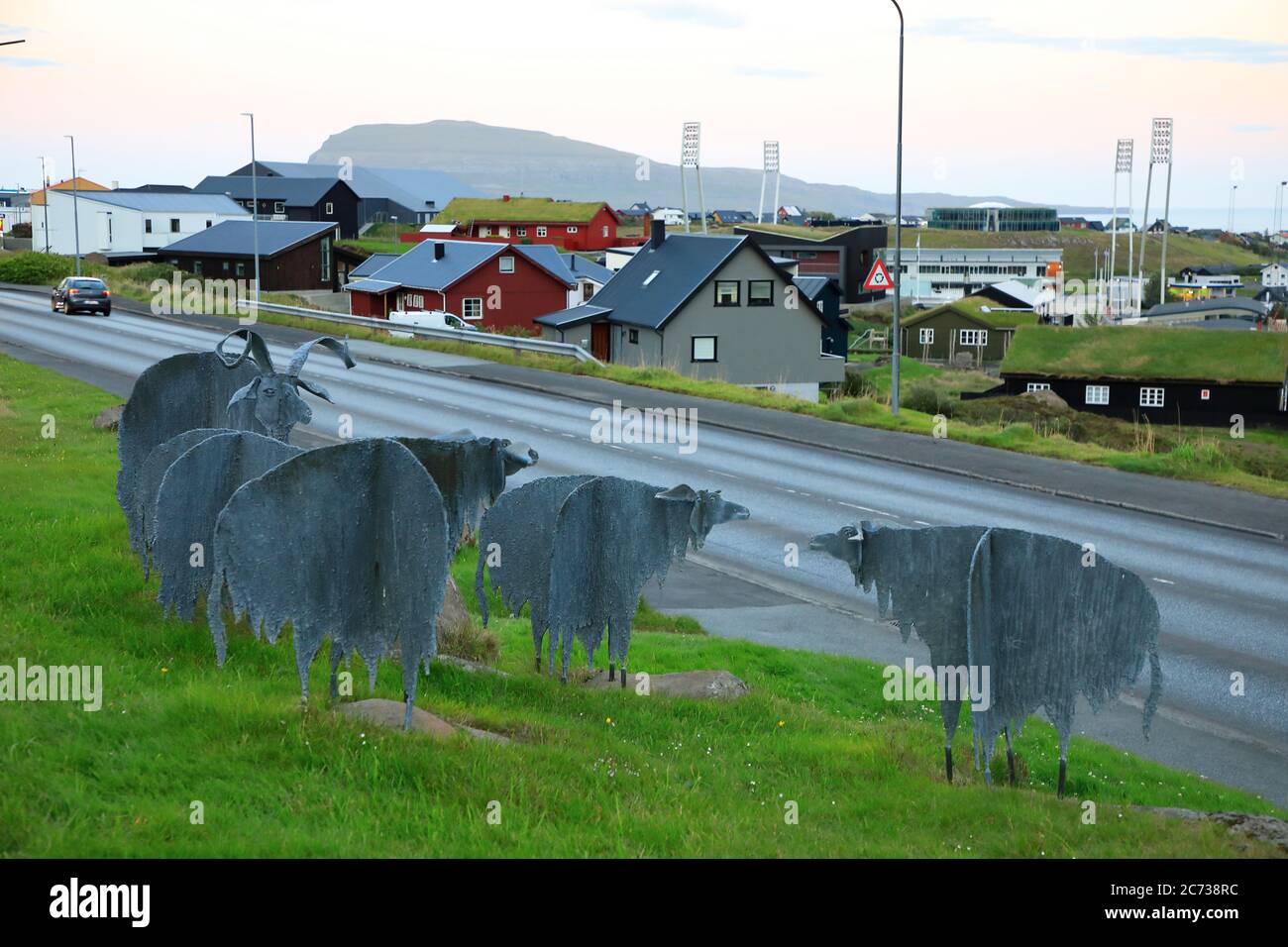 Verzinkte Eisenskulpturen von Schafen (Seydafylgi) von Bernhardt Lipsoe auf dem Boden des Nordischen Hauses mit einer Straße und einem Wohnviertel im Hintergrund.Torshavn.Färöer Inseln. Stockfoto