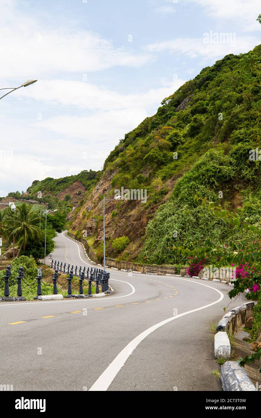 Die wunderschöne kurvenreiche Straße mit Bergen, Blumen und Meer auf zwei Seiten in Da Nang. Der Weg zu den Ba Na Hügeln in Da Nang, Vietnam. Stockfoto