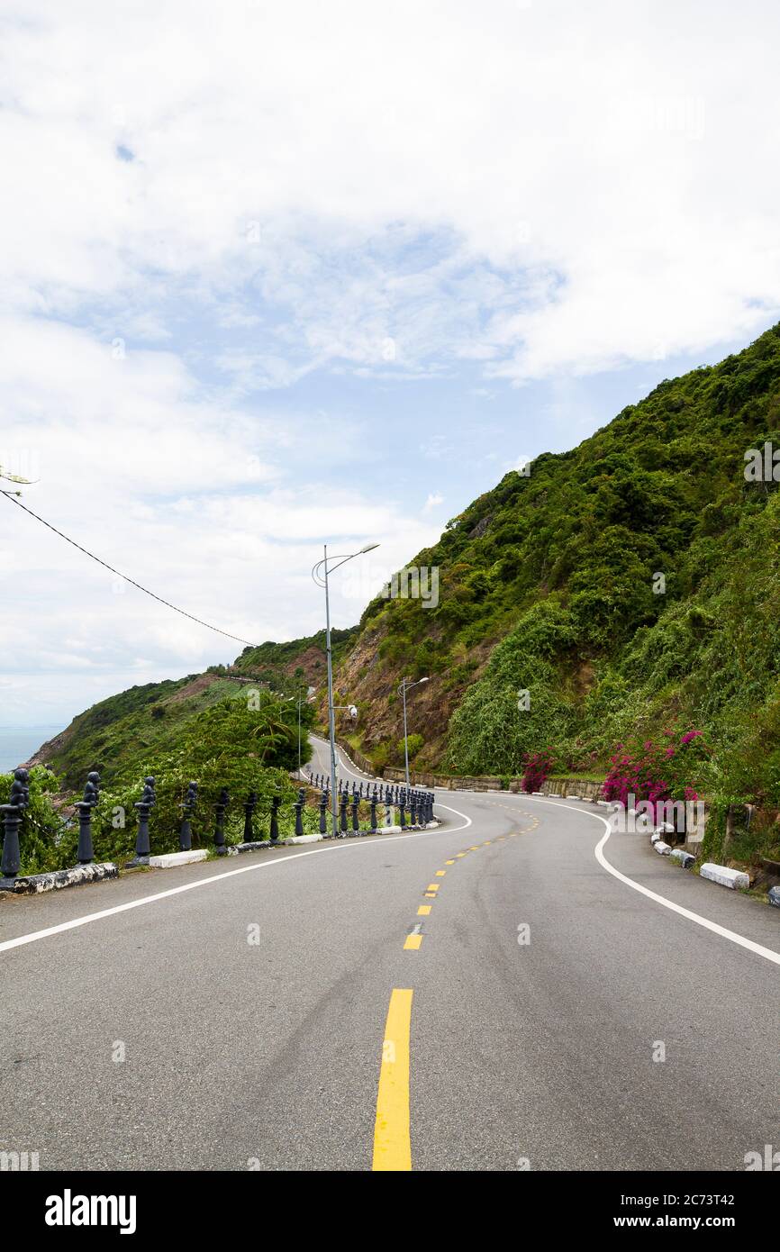 Die wunderschöne kurvenreiche Straße mit Bergen, Blumen und Meer auf zwei Seiten in Da Nang. Der Weg zu den Ba Na Hügeln in Da Nang, Vietnam. Stockfoto