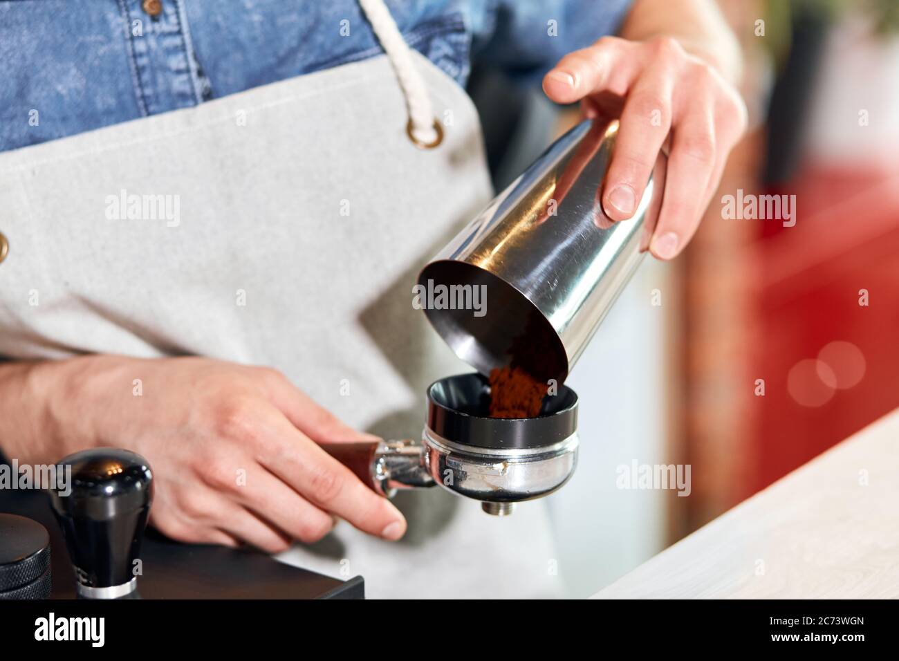 Männliche Hände bringt gemahlenen Kaffee in den Sabotagekontakt. Barista nimmt Auftrag, eine Tasse heißen aromatischen Cappuccino für freundliche Gäste aus nächster Nähe zu machen Stockfoto