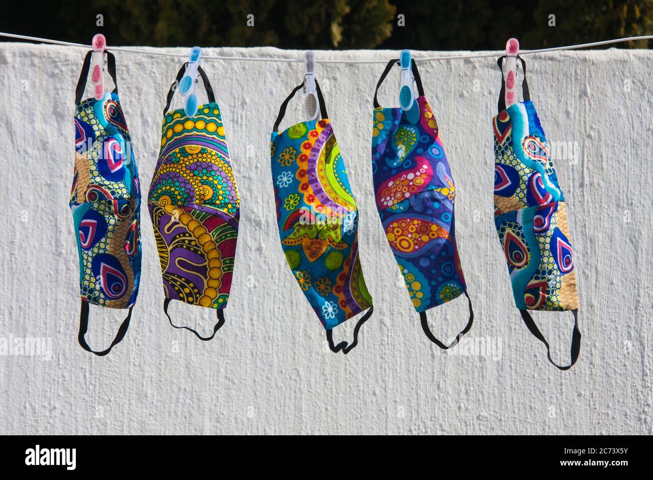 Bunte südafrikanische Stoff Gesichtsmasken für Covid-19 Schutz hängen auf einer Wäscheleine trocknen Stockfoto Bunte südafrikanische Stoff Gesichtsmasken für Covid-19 Schutz hängen auf einer Wäscheleine trocknen Stockfoto