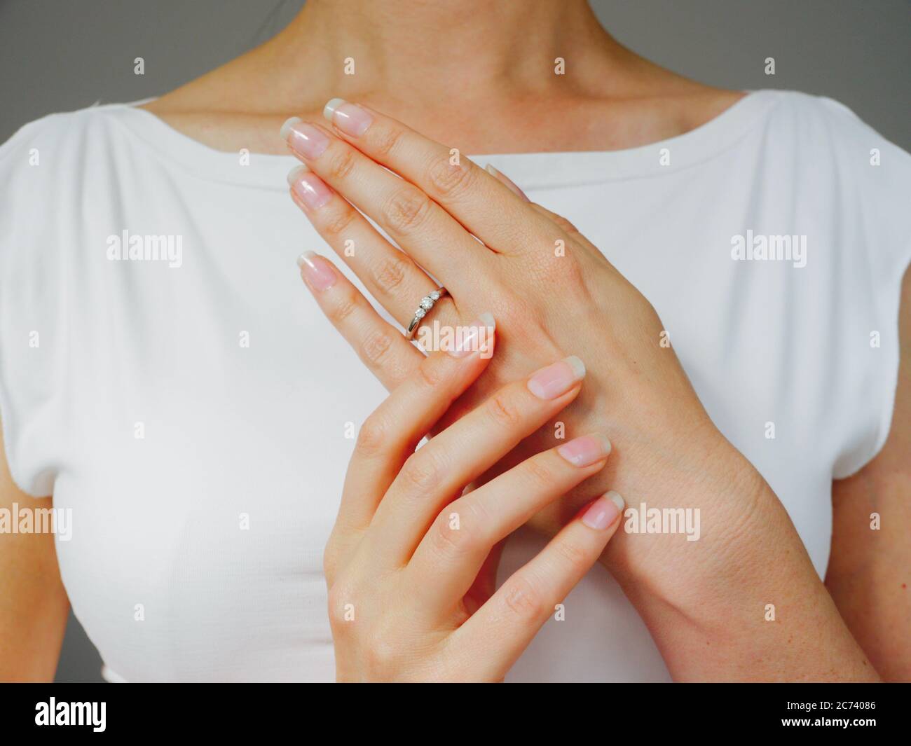 Eine Frau mit natürlichen Nägeln zeigt ihren Verlobungsring Diamond Stockfoto