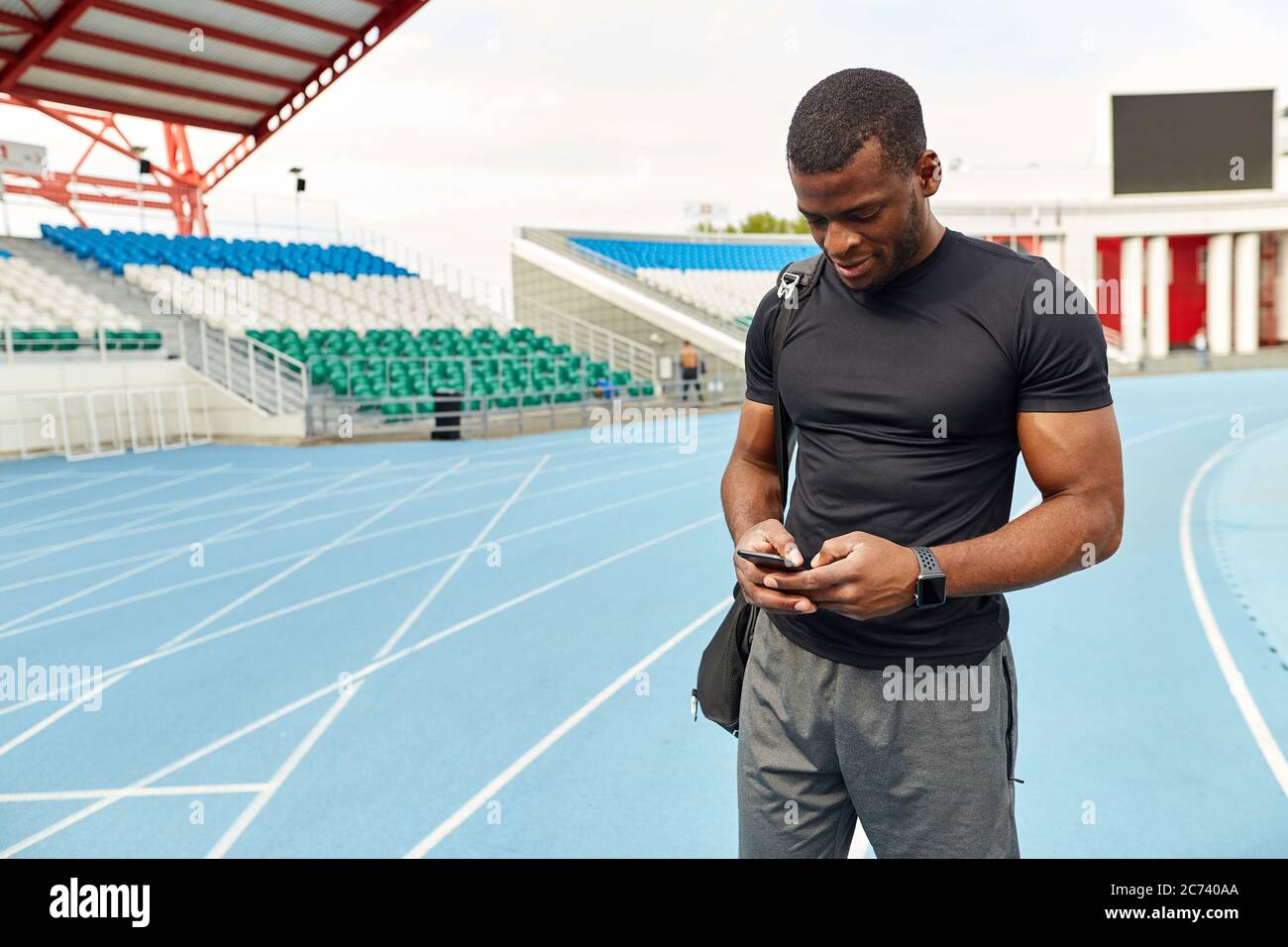 Gut aussehend lächelnden Sportler mit Handy im Stadion, Nahaufnahme Porträt, Kopierer Raum. Gadget, Technologie Stockfoto