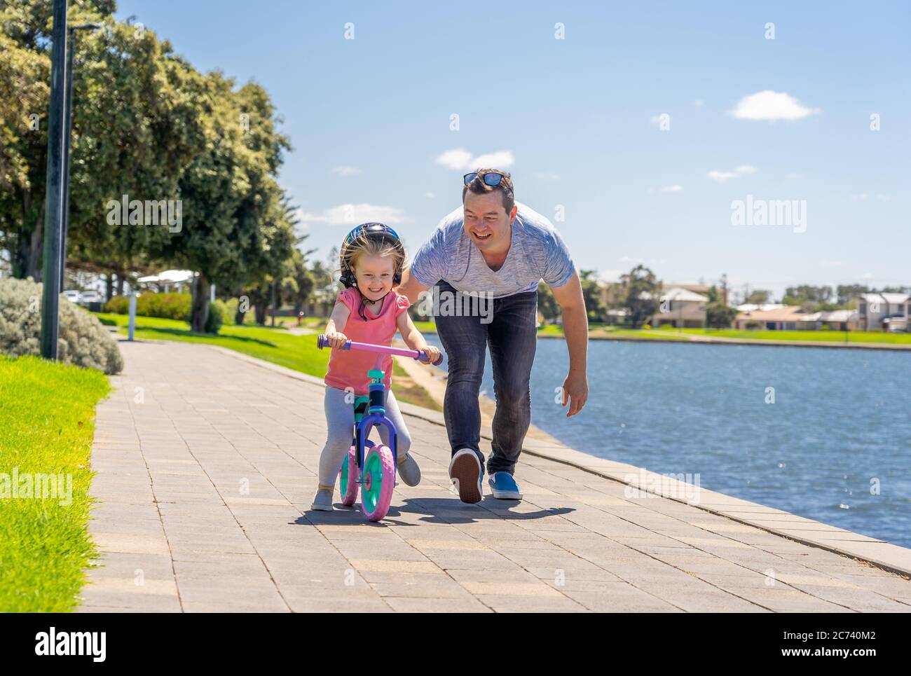 Kleines Mädchen lernen, ein Fahrrad mit seinem Vater im Park am See zu fahren. Vater und Tochter verbinden und Spaß zusammen haben. Glückliche Familie, out Stockfoto