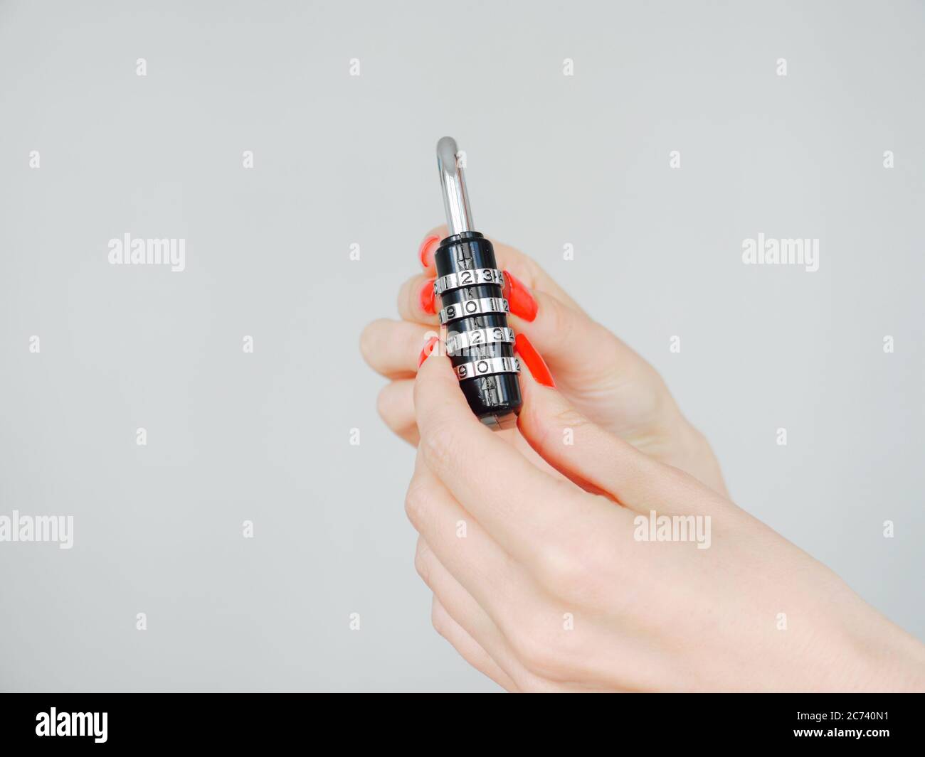 Weibliche Hände mit rot gepflegten Nägeln hält ein schwarzes Vorhängeschloss mit den Nummern 2020 Stockfoto