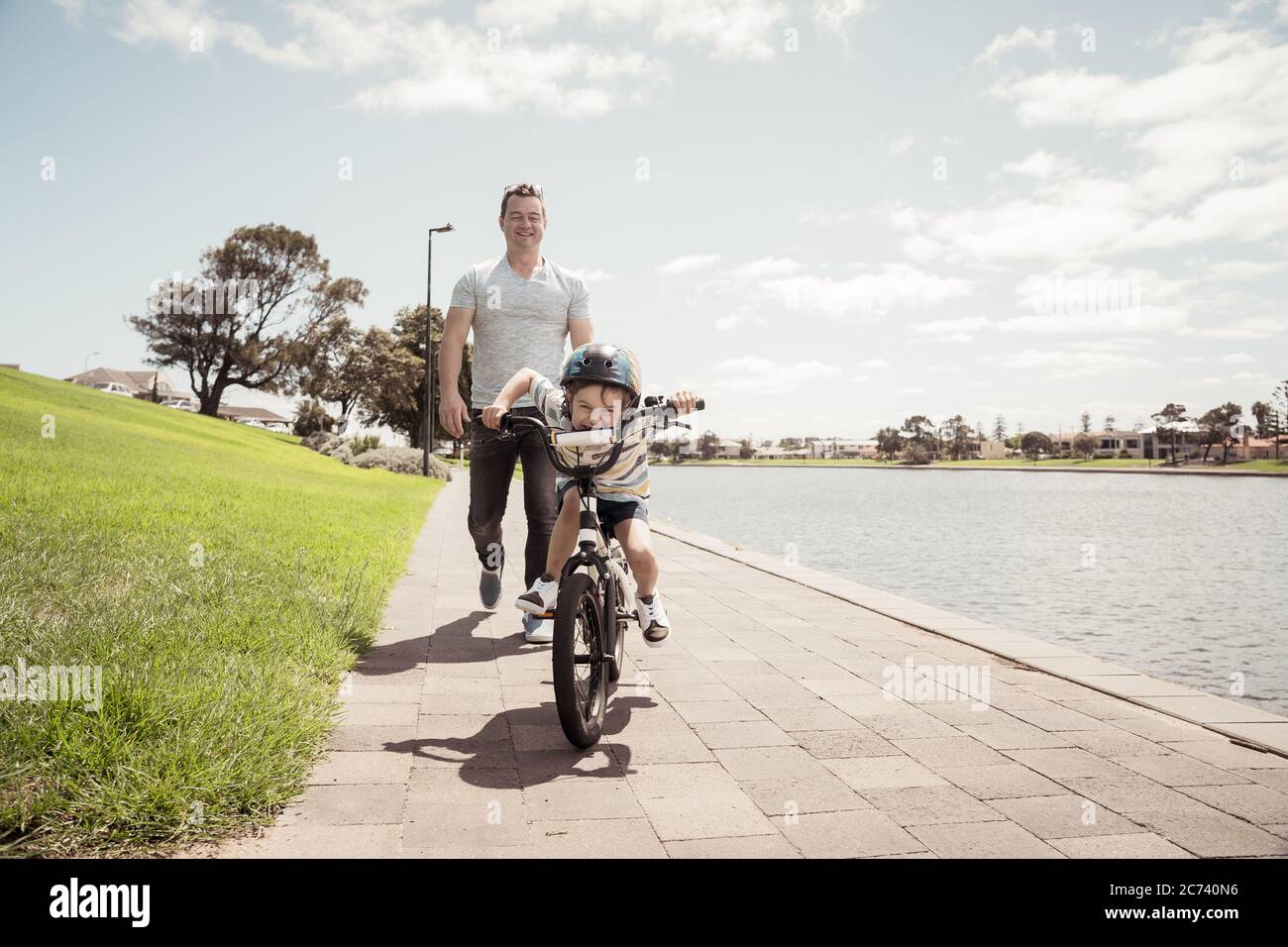 Junge lernen, ein Fahrrad mit seinem Vater im Park am See zu fahren. Vater und Sohn haben Spaß zusammen auf den Rädern. Glückliche Familie, im Freien activi Stockfoto