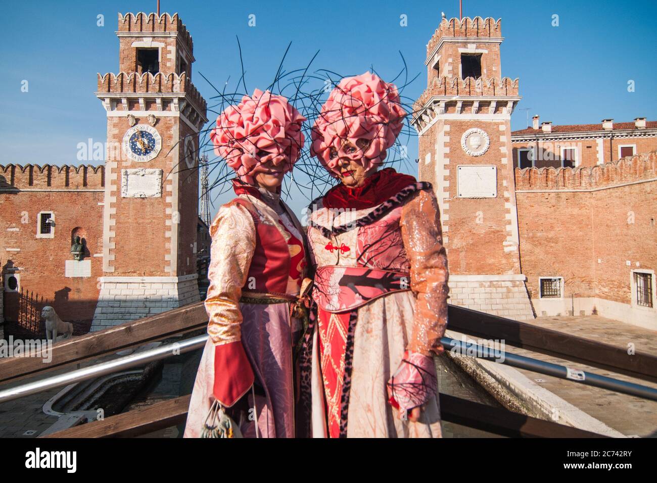 VENEDIG, ITALIEN - 28. FEBRUAR 2020: Zwei rosa und blumige Masken posieren vor dem Arsenale von Venedig während des Karnevals von Venedig Stockfoto