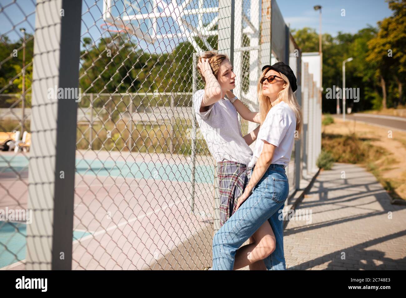 Cool Kerl stehen mit schönen Mädchen und Ordnung in seine Haare, während sie träumerisch beiseite schauen. Mädchen in Jeans und Spitzenmütze verbringen Zeit mit Jungen auf Stockfoto