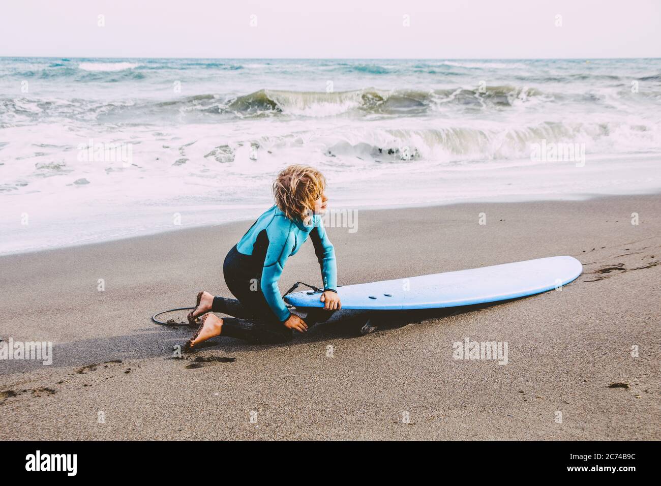 Ein kleiner Junge, der an einem sonnigen Sommertag im Body Board im Freien an der Küste lernt Stockfoto