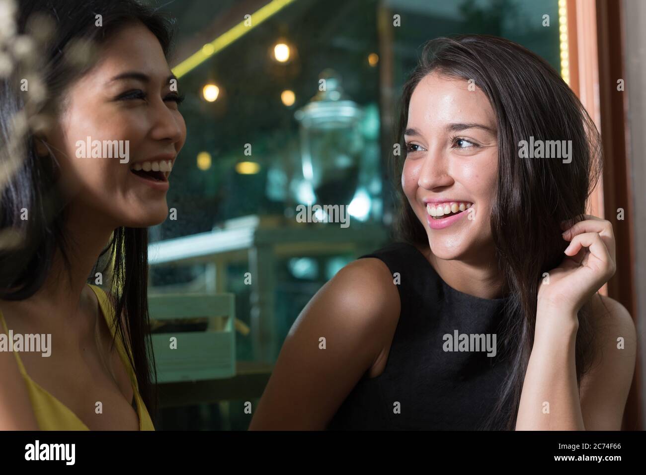 Zwei glückliche junge schöne Frauen lächeln zusammen im Café Stockfoto