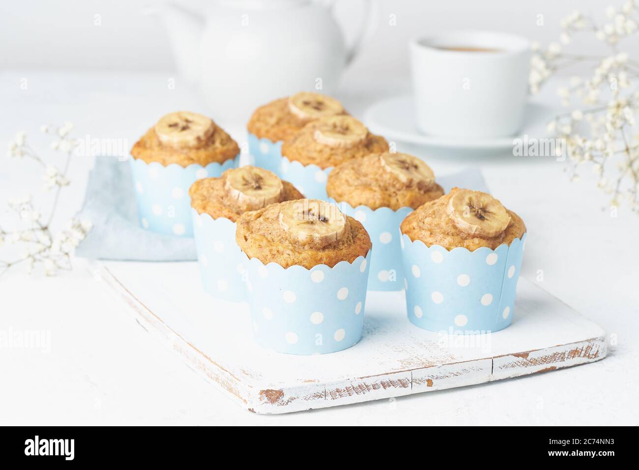 Bananenmuffin, Cupcakes in blauen Kuchenhüllen Papier, weißer Betontisch Stockfoto