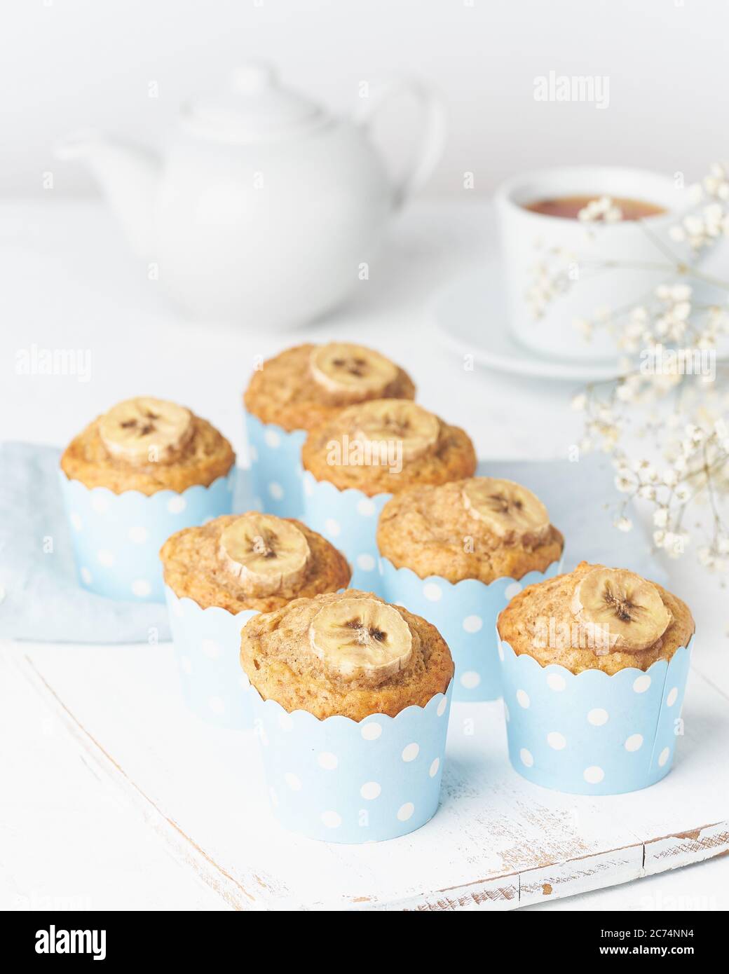 Bananenmuffin, Cupcakes in blauen Kuchenhüllen Papier, weißer Betontisch Stockfoto
