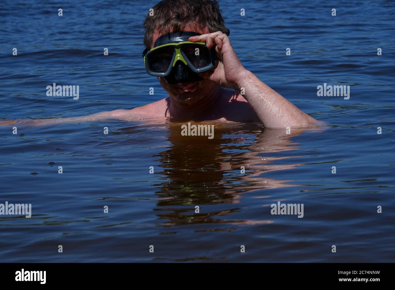 Ein Typ in einer Tauchmaske taucht aus dem Wasser Stockfoto