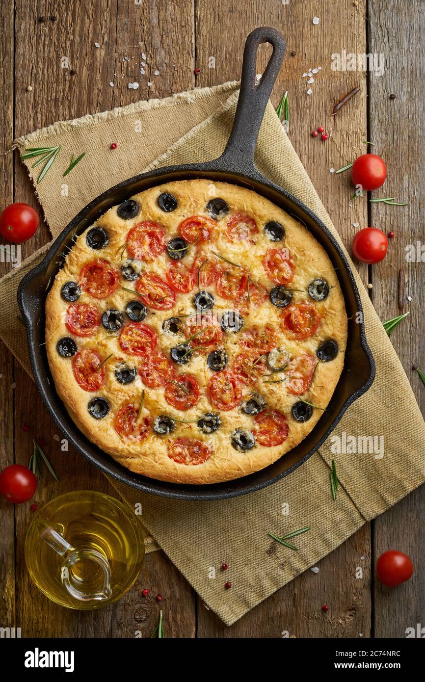 Focaccia, Pizza in Pfanne, italienisches Fladenbrot mit Tomaten, Oliven und Rosmarin Stockfoto