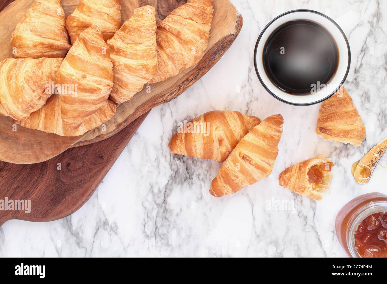 Frische, hausgemachte Croissants oder Halbmond Brötchen mit Marmelade und einer Tasse Kaffee über Marmor Hintergrundbild Schuß von der Ansicht von oben. Stockfoto