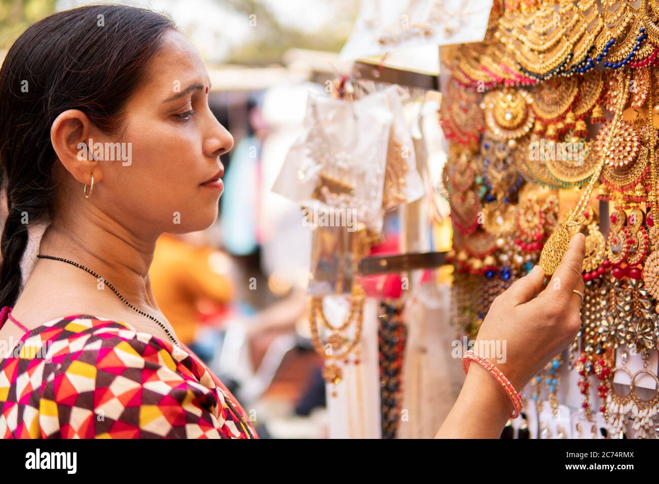 Indische reife Frau suchen und kaufen Ohrringe, Schmuck aus Outdoor-Straßenmarkt von Delhi, Indien am Tag Zeit. Sie ist in ihrer traditionellen indischen dres Stockfoto