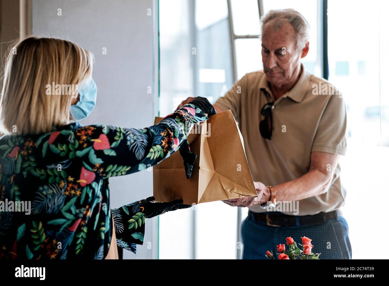 Take-away-Service an der Restauranttür - Arbeiter, der dem Kunden verpackte Speisen gibt Stockfoto